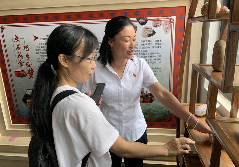 1_钟丽眉（右）向中国妇女报·中国妇女网记者介绍手绘鹅卵石.jpg